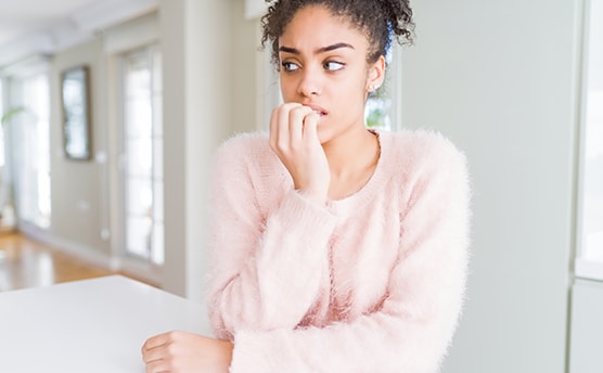 femme avec pull rose se rongeant les ongles